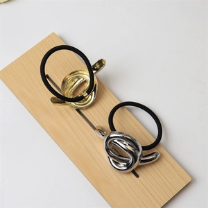 Close-up of polished gold and silver metallic knot hair ties on a wooden display stand