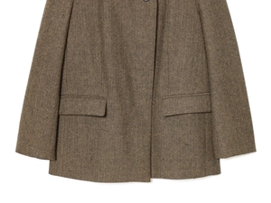 Detail of herringbone wool blazer showing flap pockets and textured weave fabric