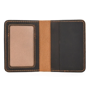 Detail view of leather card holder with dual color panels and orange contrast stitching