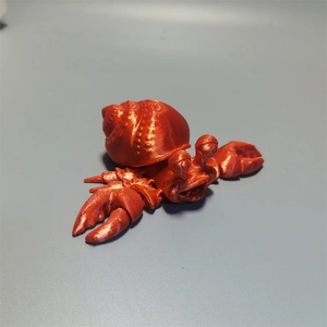Detail shot of a red 3D printed hermit crab toy with visible layered surface texture