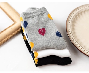 Detail of stacked cotton socks with heart patterns in gray, white and black colors