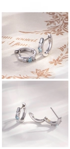 Detailed view of silver hoop earrings with round light blue zircon and claw setting design