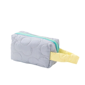 Quilted light blue makeup bag with yellow handle and mint green zipper on white background