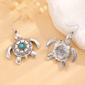 Detail of vintage silver sea turtle earrings with turquoise gemstone and boho patterns