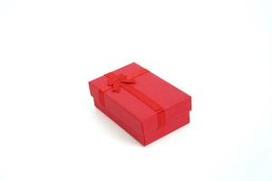 Top view of a red jewelry gift box with a matching silk ribbon bow on white background