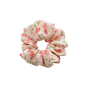 Chiffon floral scrunchie with pink flowers and green leaves on an off-white background