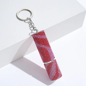 Lipstick-shaped keychain with pink and red rhinestones on white geometric background