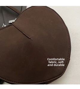 Detail der herzförmigen dunkelbraunen mattem Ledertasche mit Silber-Reißverschluss und Naht
