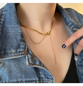 Close-up of golden snake chain necklace with bead pendant on model neck