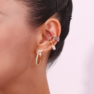 Close-up of gold hoop earrings with pearls and silver wave ear cuff on female ear