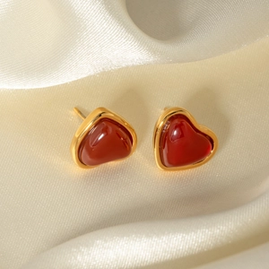 Detailed macro view of vintage gold-plated heart earrings on white silk fabric