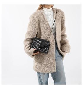 Close-up of a black quilted crossbody bag with V-shaped stitching and a chain strap