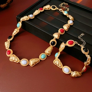 Close-up of vintage gold necklace and bracelet set with colorful oval stones on leather