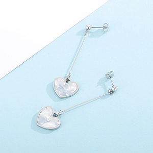 Detailed view of long dangling heart earrings with marble texture on a dual-tone background