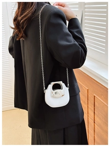 Close-up of white mini crossbody bag with silver circular handle and chain strap