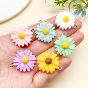 Macro view of colorful resin daisy charms held in hand for jewelry making diy