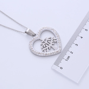 Macro shot of silver heart-shaped Tree of Life necklace with dimensions on a metric ruler