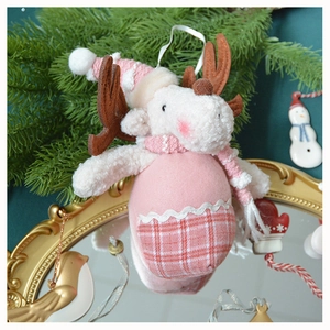 Detail of pink plaid plush reindeer ornament on a gold mirror with festive pine branches