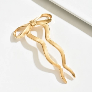 Elegant gold bow hair pin with wavy metal prongs for minimalist women's hair styling