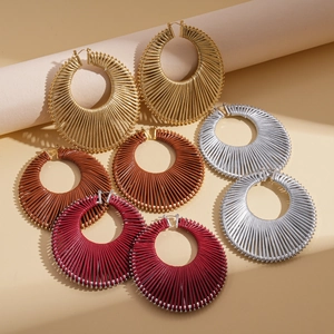 Macro view of woven geometric hoop earrings in gold, silver, brown, and red colors