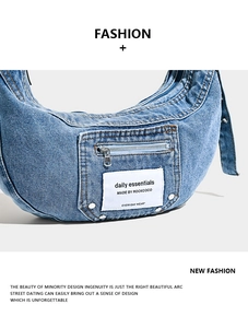 Detailed close-up of retro washed blue denim crescent bag with zipper pocket and label