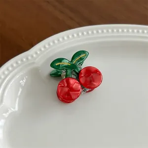 Detail shot of cute red cherry hair claw clip on an elegant white ceramic plate