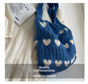 Detail of blue cable knit tote bag featuring cream heart pattern on pleated skirt