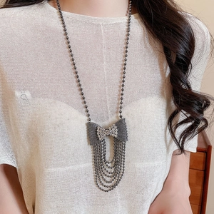 Detail view of a dark metal bow pendant necklace with sparkling diamonds and tassels