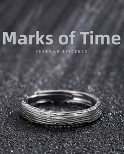 Macro shot of silver ring with unique tree bark texture on a sleek dark surface