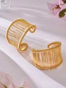 Détail de deux bracelets manchettes dorés tissés avec texture de fil métallique sur bois