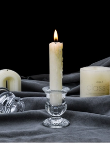 Macro shot of elegant fluted glass candle holder with candle on dark vintage fabric