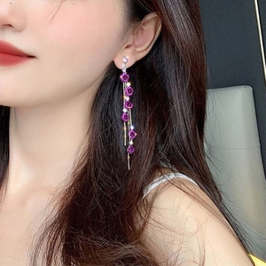 Detail of purple rose earrings with rhinestone tassels shown on a female model