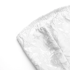 Vue détaillée du tissu jacquard blanc à fleurs avec des finitions élastiques