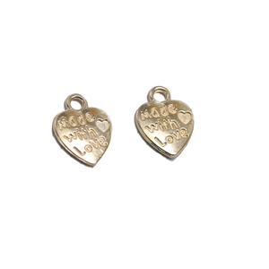 Detalle de colgantes de corazón en aleación dorada con grabado para joyería artesanal