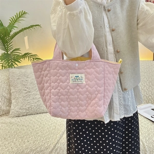 Close-up of pink quilted handbag featuring heart patterns and white HAPPY logo patch
