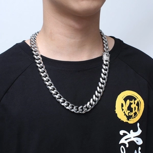 Close-up of a silver Cuban chain necklace with a diamond-encrusted clasp on a male model