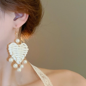 Gros plan sur des boucles d'oreilles cœur en raphia avec perle sur le mannequin
