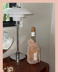 Detail of pink crystal beaded wine bag with leather handle and sparkling champagne bottle
