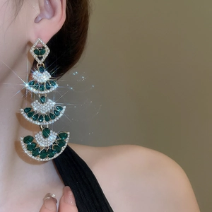 Close-up of vintage emerald fan tassel earrings with sparkling zircons on a model