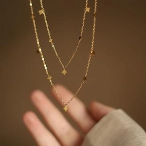 Detail of double-layer gold titanium steel necklace with small rhombus-shaped pendants