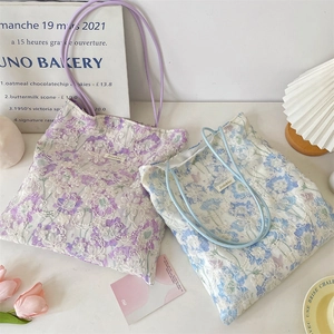 Detailed embroidery of floral lace patterns on purple and blue canvas tote bags