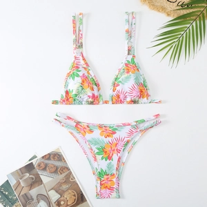 Flat lay of a floral bikini set with tropical palm leaf pattern and summer accessories