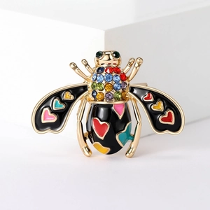 Detail of bee brooch with golden metal wings, black enamel, and colorful heart patterns