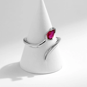 Minimalist silver snake ring with red teardrop gemstone on white conical stand