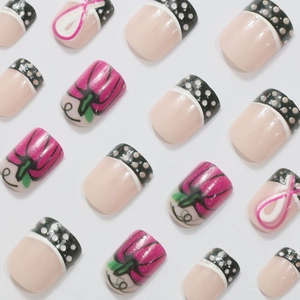 Short square press-on nails with pink floral motifs, black polka dots and ribbon designs