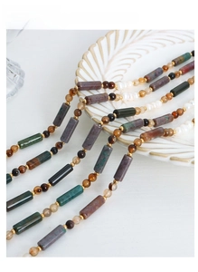 Macro detail of multi-strand necklace with natural stones and pearls on shell tray