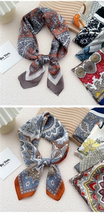 Detail of elegant paisley silk scarves in orange and blue tones on wooden display