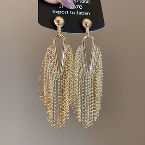 Detail view of gold tassel earrings with multi-layer bead chains and metallic luster