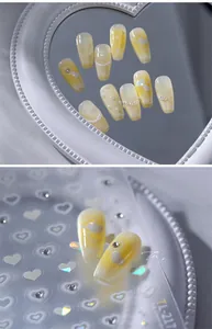 Detail of yellow long coffin press-on nails with 3D pearls and heart patterns