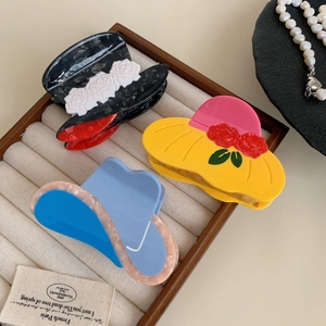 Three acetate hair claws in cowboy hat design with floral details on white fabric